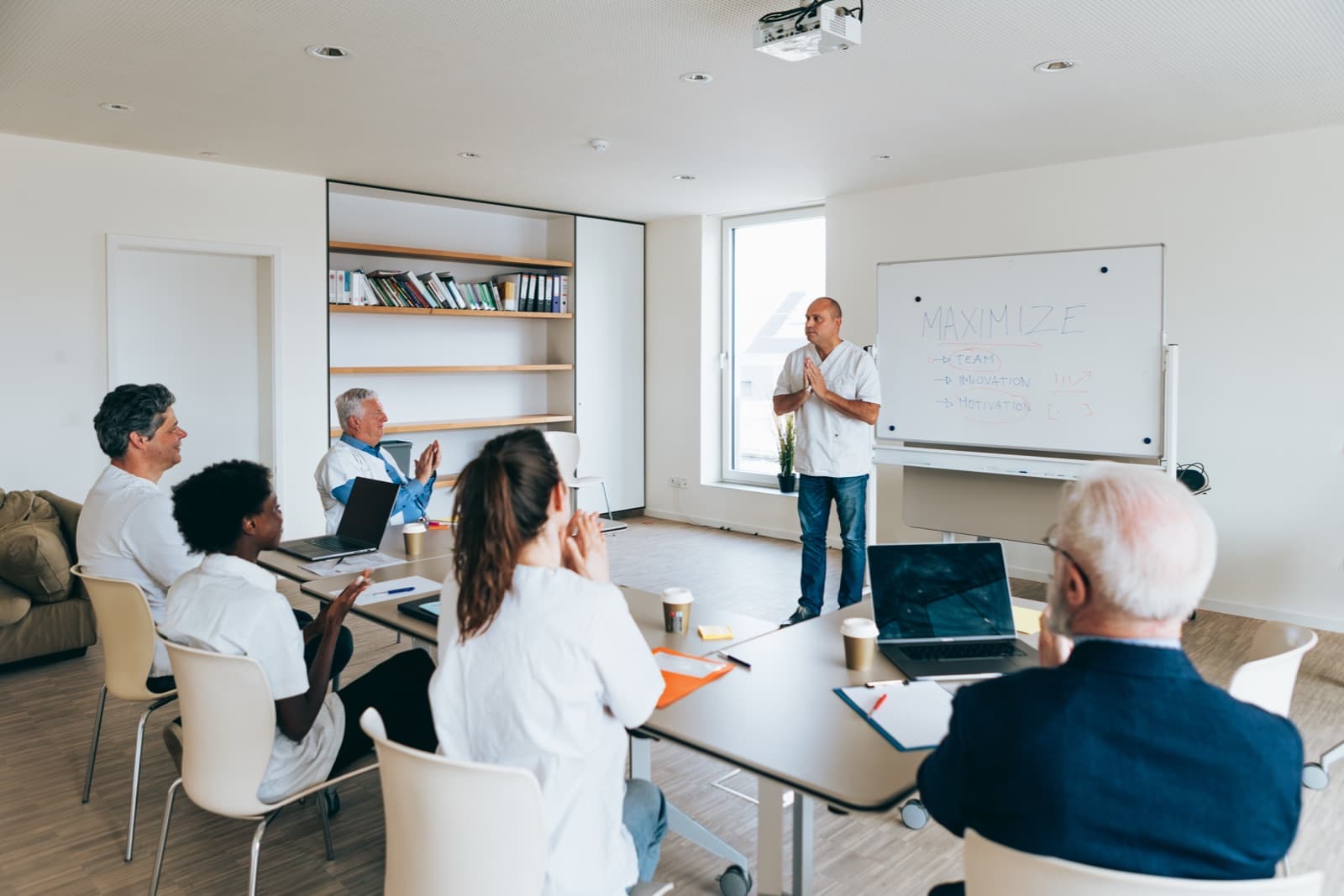 A trainer presenting at a whiteboard to a seated group during an on-site session